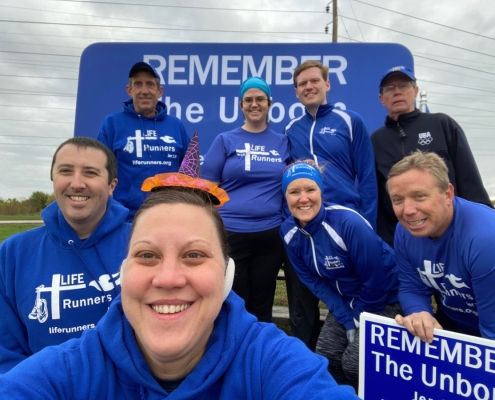 Many people taking picture in front of sign.