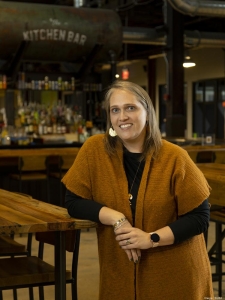 Dr. Amy Bilyeu smiling while standing at wooden table in restaurant setting.
