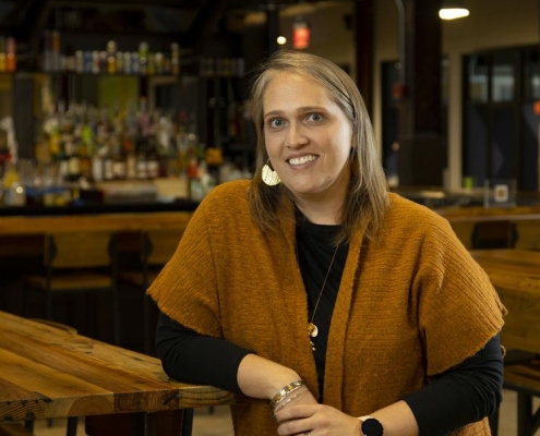 Dr. Amy Bilyeu smiling while standing at wooden table in restaurant setting.