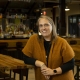 Dr. Amy Bilyeu smiling while standing at wooden table in restaurant setting.